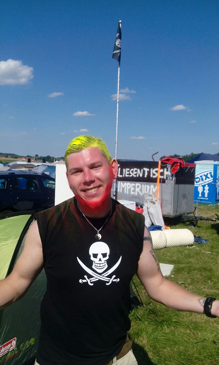Mensch mit Sonnenuntergangshut auf weiter Festivalwiese