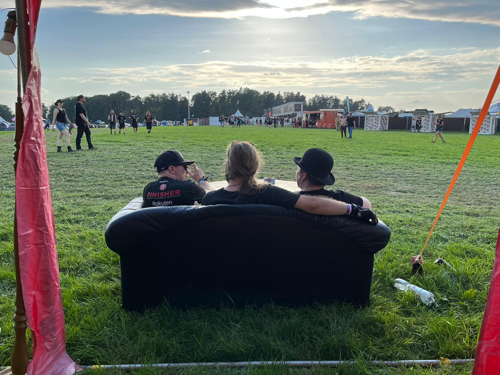 Drei Personen auf Sofa blicken auf Festivalgelände